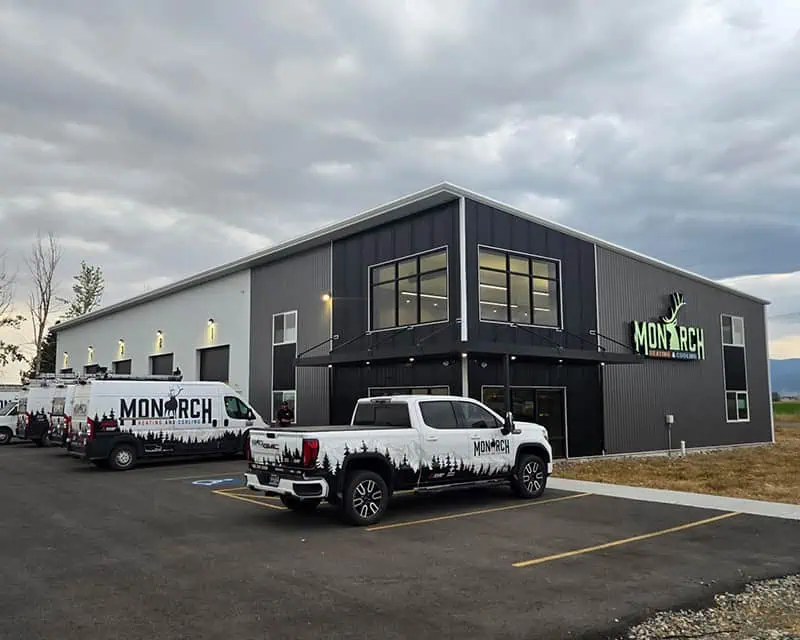 Monarch Heating commercial steel building exterior at dusk with branded fleet vehicles