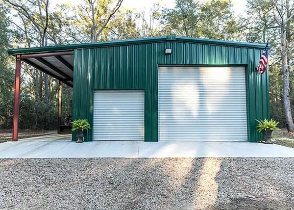 Green steel storage building with two roll-up doors and lean-to